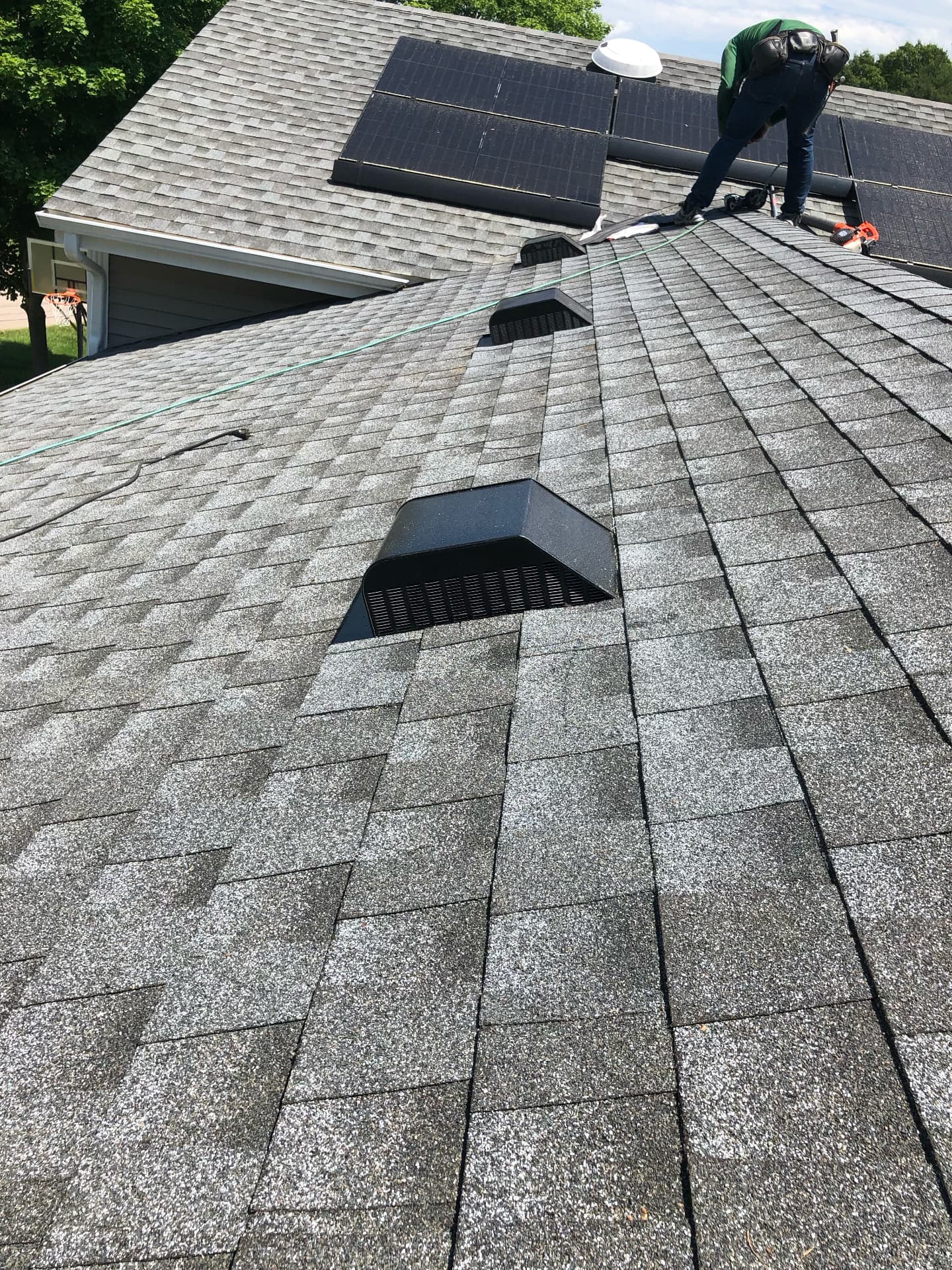 New architectural shingles and roof vents installed around solar panels