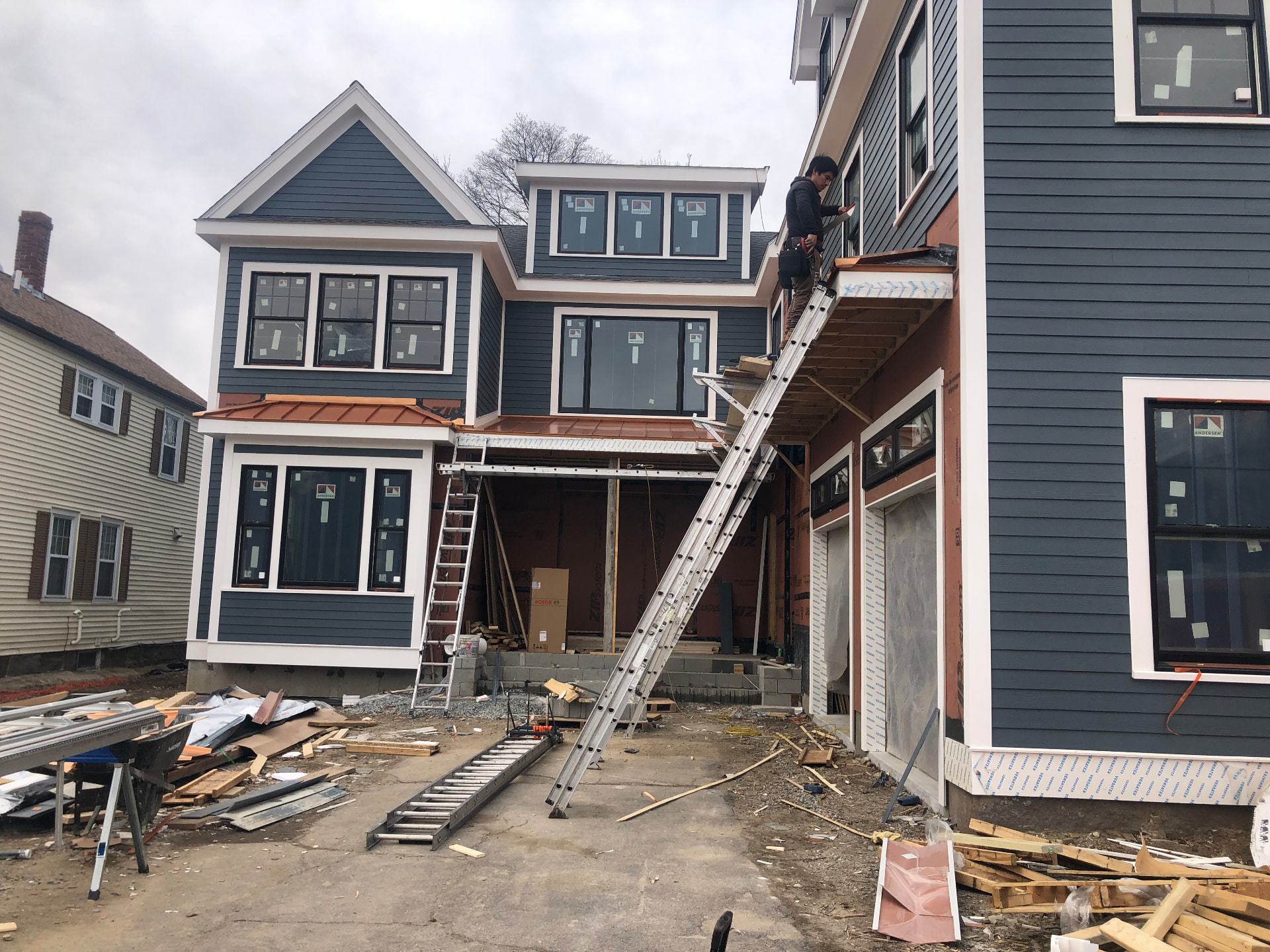 Copper metal roof over bay windows on a new blue-sided home