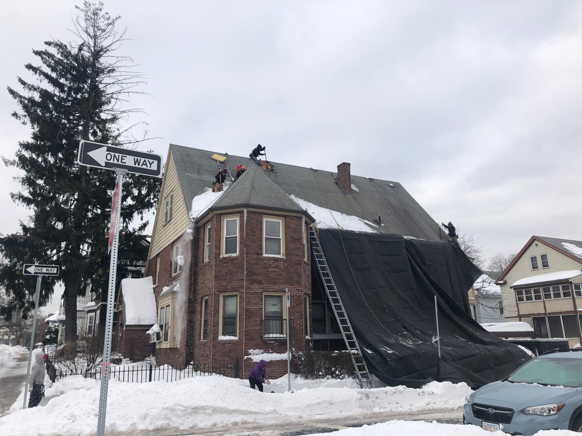 Crew tearing off an old roof on a brick home in winter